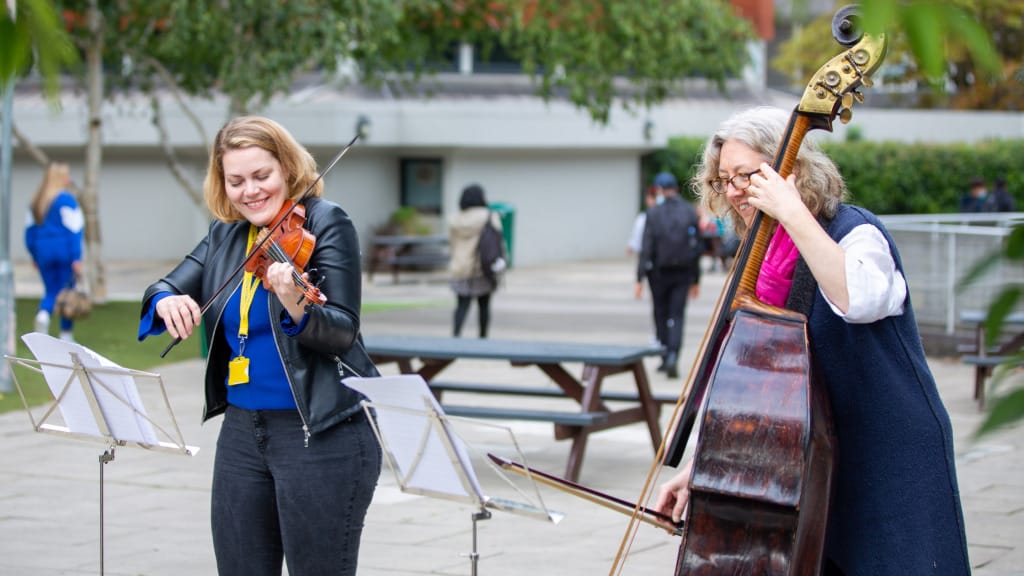Violinist Julia Kuhn and bass player Cecelia Bryggemyer playing in the playground at Acland burghley School