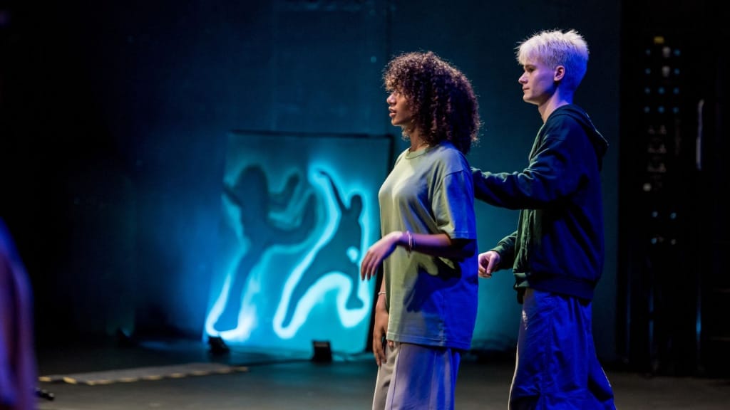 A young male street dancer standing behind a young female dancer with his hand on her back