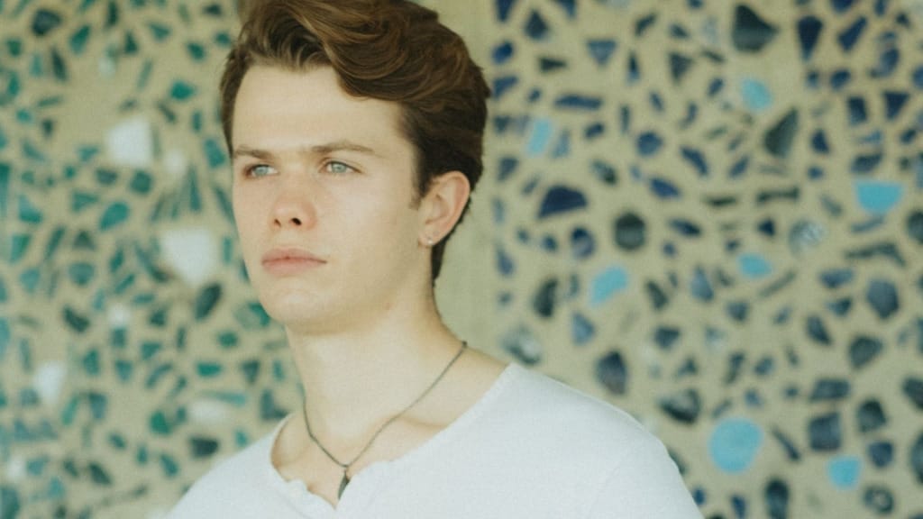 A head and shoulders phoro of the tenor Hugo Brady, a white man with wavy brown hair and blue eyes.