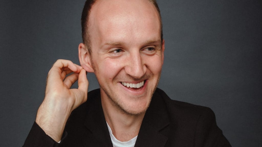 A headshot of the baritone Peter Edge, a white man with short hair who is smiling.