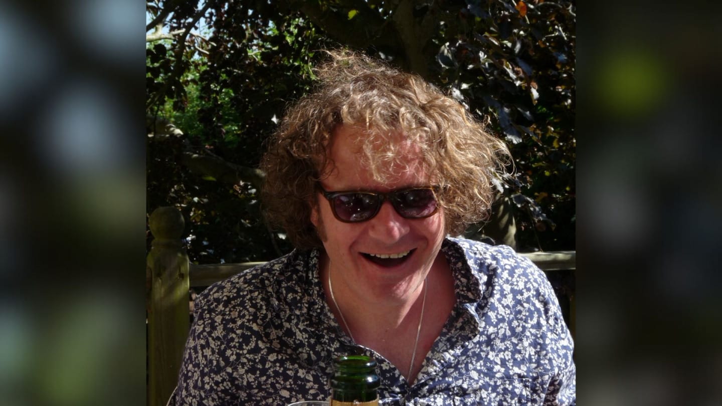 An informal photo of David Watkin (cellist) wearing shades and having a picnic near woods