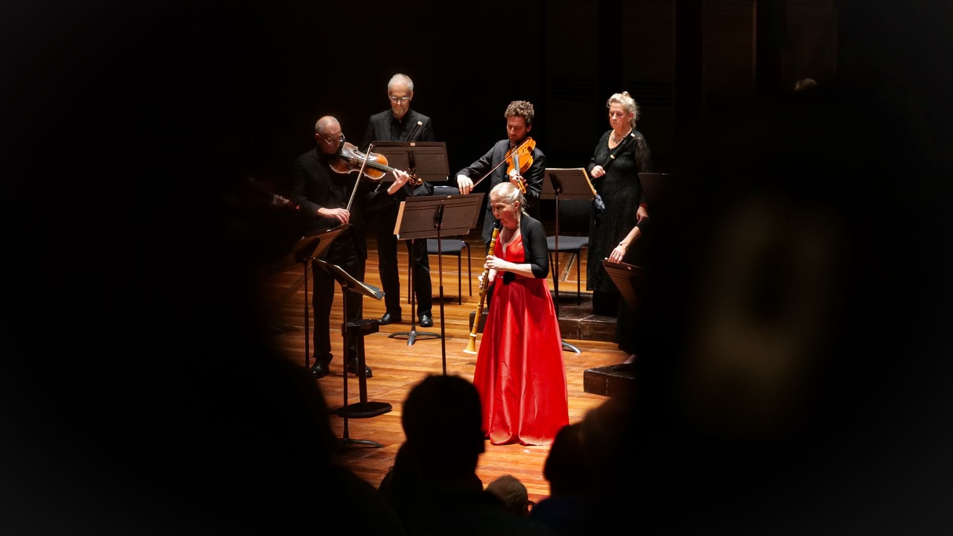 Katherine Spencer, in a red dress, performing Mozart's Clarinet Concerto with members of the Orchestra of the Age of Enlightenment